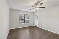 Bright room with elegant wood flooring, large window, and modern ceiling fan, perfect for comfortable living.