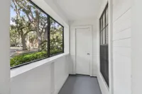 Inviting enclosed porch with large windows showcasing a serene view of lush trees, perfect for relaxing and enjoying nature.