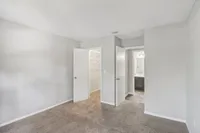 Bright and spacious bedroom with plush carpeting, featuring a walk-in closet and an adjoining bathroom with modern fixtures.