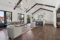 Elegant open-concept clubhouse with vaulted ceilings, featuring modern lighting, cozy seating, and a chic kitchen with bar stools and stylish decor.