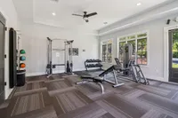 Bright and inviting gym room featuring modern workout equipment, free weights, and large windows letting in natural light.