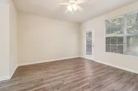 Bright and airy room with sleek hardwood floors, a ceiling fan, and large windows offering scenic views.