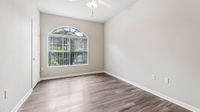 Bright and inviting bedroom featuring elegant hardwood floors, large arched window, and soothing neutral walls.