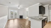 Chic open-concept living space featuring sleek hardwood floors, a contemporary granite kitchen, and a cozy fireplace with elegant French doors opening to a scenic view.