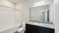 Elegant bathroom with granite countertop, large mirror, and modern lighting fixtures, offering a serene retreat.