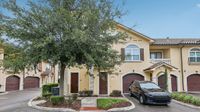 Charming townhouse with classic architecture, lush greenery, and attached garage in a serene neighborhood setting.