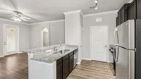 Sleek modern kitchen with granite countertops, stainless steel appliances, and elegant wood flooring in a bright, open-concept space.