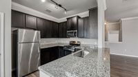 Modern kitchen with sleek granite countertops, stainless steel appliances, and dark wood cabinetry, perfect for culinary enthusiasts.