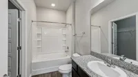 Modern bathroom featuring a sleek granite countertop, spacious bathtub, and elegant fixtures, perfect for relaxation.