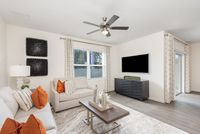 Bright and modern living room featuring sleek decor, plush seating with vibrant pillows, and a large wall-mounted television, perfect for relaxation and entertaining.