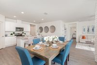 Chic open-plan living area with a modern kitchen, elegant dining setup, and inviting living room. Features vibrant blue chairs and tasteful decor.