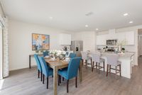 Modern dining area with vibrant blue chairs, elegant table setting, and charming decor adjacent to a sleek open-concept kitchen.