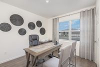 Bright and inviting home office with modern decor, featuring a sleek wooden desk and comfortable seating, complemented by stylish wall accents and a large window with a scenic view.
