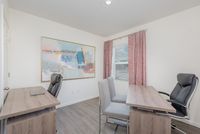 Bright and inviting home office with modern desks and sleek chairs, highlighted by a large abstract painting and natural light from a window with chic curtains.