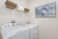 Modern laundry room with sleek appliances, elegant wall art, and convenient shelving.