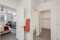 Modern apartment hallway with access to a bright bedroom, sleek bathroom, and spacious walk-in closet, highlighting chic decor and elegant flooring.