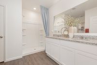 Bright and elegant bathroom featuring a spacious walk-in shower, sleek granite countertops, and modern cabinetry.