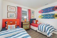 Vibrant nautical-themed bedroom with two cozy twin beds adorned in blue and white stripes, surfboard wall decor, and colorful ocean-inspired accents.