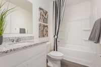 Modern bathroom featuring elegant granite countertop, sleek white cabinetry, and stylish gray accents for a contemporary feel.