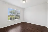 Bright, unfurnished room with elegant dark hardwood floors and large window with scenic outdoor view.