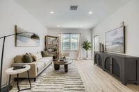 Bright and modern living room featuring a cozy beige sofa, stylish artwork, and abundant natural light from large windows.