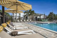 Premium outdoor pool area with elegant sun loungers, striped umbrellas, and lush greenery, perfect for relaxation and leisure.