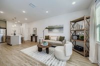 Contemporary open-plan living room with a cozy sofa, elegant decor, chic shelving, and a modern kitchen with stainless steel appliances.