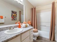 Bathroom with large mirror, bright lighting, tub with shower combination