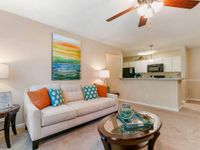 Inviting living room, ceiling fan and light, breakfast bar into kitchen