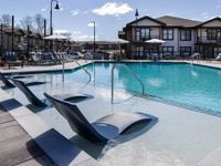 Large and shimmering pool with lounge chairs, and sun-bathing space