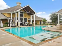 Inviting apartment complex pool area with elegant lounge chairs and a stylish clubhouse.