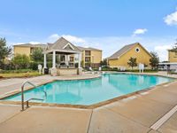 Inviting apartment complex pool area with elegant shaded pavilion and lush landscaping.
