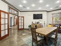 Spacious dining room featuring wooden furniture, large windows, and stylish decor.