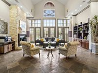 Luxurious living room with high ceilings, natural light, and chic decor featuring a stone fireplace and comfortable seating.