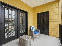 Inviting balcony with vibrant yellow walls showcasing a wicker chair and glass panel doors.