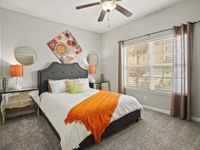 Inviting bedroom with plush gray headboard, vibrant orange throw blanket, and artistic wall decor.