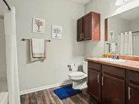 Chic bathroom with modern fixtures, wood cabinetry, decorative wall art, and a clean, minimalist design.