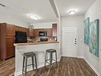 Modern kitchen entrance with sleek bar stools, wooden cabinets, and stylish decor.