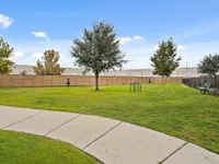 Vibrant green community park area with trees, a bench, and walkway in an apartment complex.
