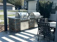 Inviting outdoor barbecue space with two modern grills and stylish seating, perfect for entertaining.