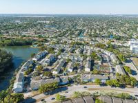 Aerial view of a charming residential neighborhood with well-maintained homes and lush greenery, showcasing a serene lakeside setting and ample community amenities.