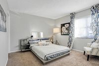 Elegant bedroom with cozy bed, chic striped bedding, stylish decor, and ample natural light.
