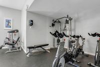 Modern apartment gym featuring spinning bikes, weight bench, and versatile exercise equipment for a complete workout experience.