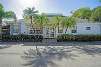 Charming white house with lush palm trees and manicured landscaping, creating a welcoming and tropical ambiance.