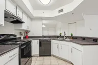 Modern kitchen with sleek black appliances, ample counter space, and stylish white cabinetry. Bright and inviting layout perfect for culinary enthusiasts.