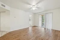Bright and airy living room with elegant wood flooring and natural light from sliding glass doors.