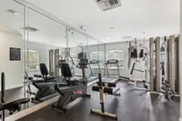 Modern fitness center with state-of-the-art equipment, mirrored walls, and large windows for natural light.