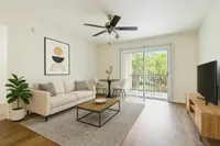 Bright and modern living room with a cozy beige sofa, elegant wall art, and a large window offering a serene garden view, perfect for relaxation and entertaining.