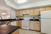 Modern kitchen with sleek black countertops, ample wooden cabinetry, and essential appliances for an ideal cooking space.