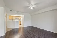 Bright and spacious living area with elegant dark wood flooring and open access to a modern kitchen.